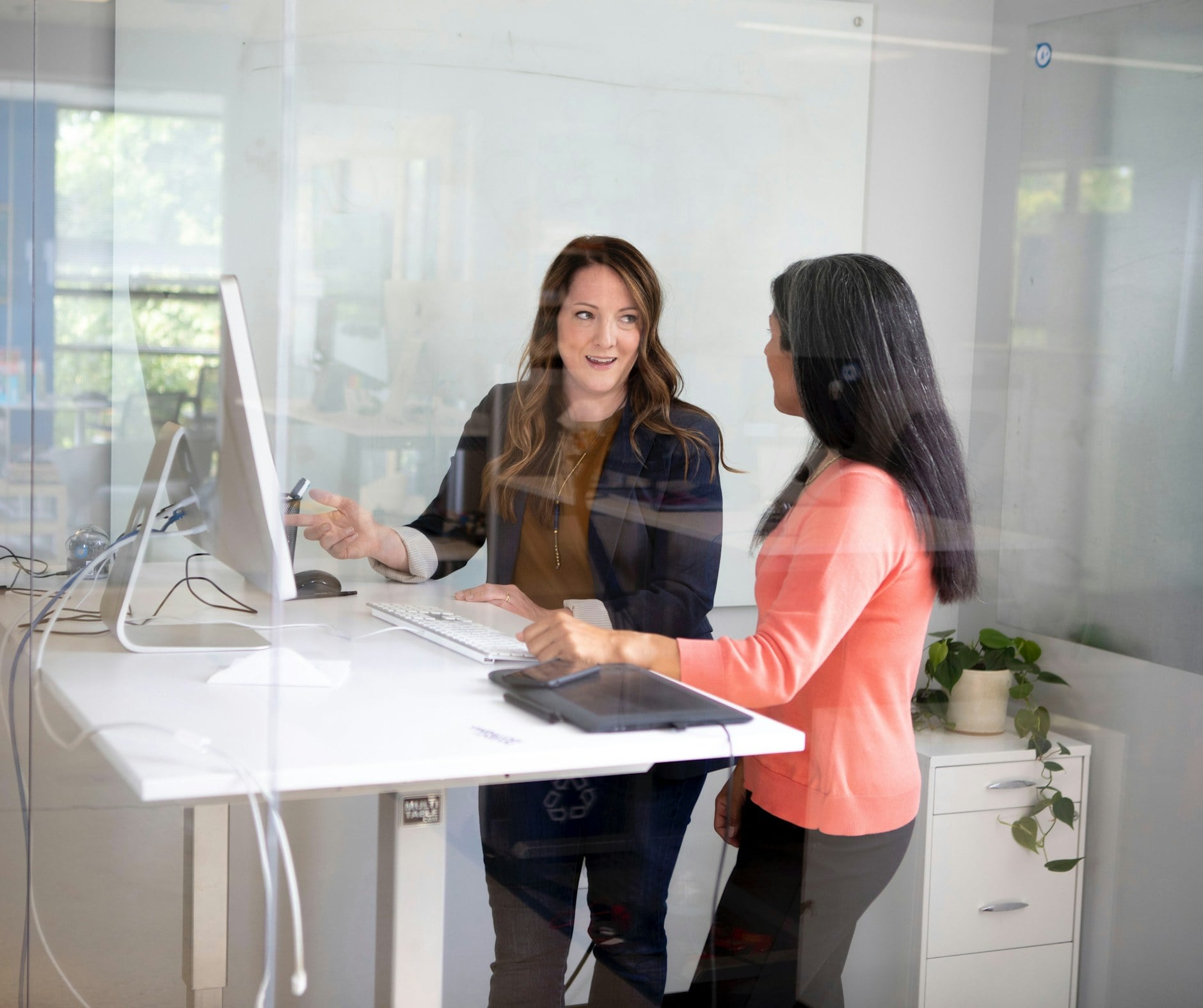 Two colleagues having a supportive conversation at a standing desk in a bright office